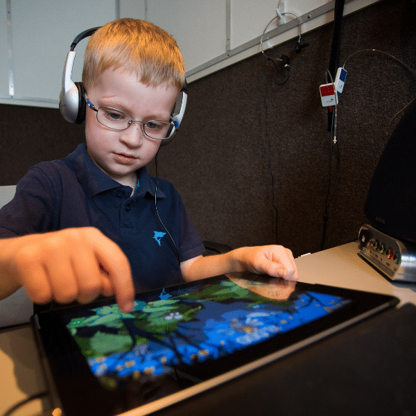 a child wearing headphones and using a tablet